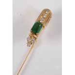 A yellow metal, emerald and diamond stick pin, featuring a step cut emerald with a trefoil of