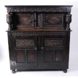 An antique joined oak court cupboard, having a rosette carved frieze above twin panelled doors