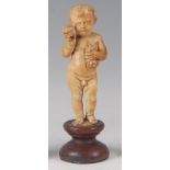 A 19th century continental carved ivory figure of a standing nude boy, holding a bunch of grapes and