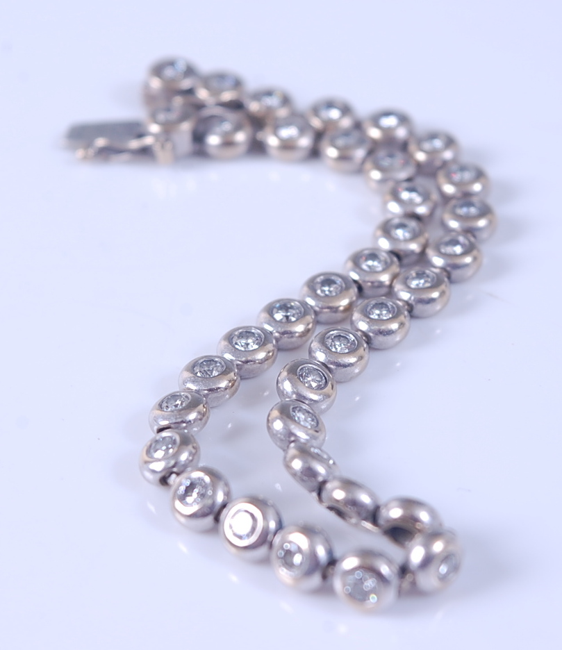 An 18ct white gold diamond line bracelet, comprising 36 round brilliant cut diamonds in rubover