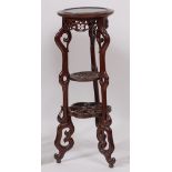 An early 20th century Chinese carved hardwood circular urn stand, raised on pierced trailing