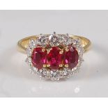 An 18ct yellow and white gold, ruby and diamond triple cluster ring, featuring three oval faceted