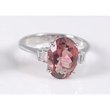 A white metal, pink tourmaline and diamond ring, featuring an oval pink tourmaline in a four-claw