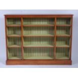 A large oak freestanding open bookshelf, comprised of three divisions, each with adjustable shelves,