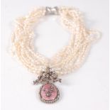 A ten row twisted baroque freshwater pearl necklet, with an oval pendant in pink guilloche with