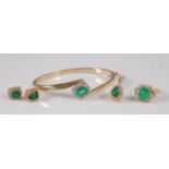 A 14ct gold, emerald and diamond suite of jewellery, comprising hinged bangle, pair of ear studs,