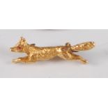 A yellow metal running fox brooch, with clip fastening, the three-dimensional fox having a