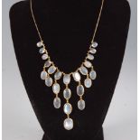 A contemporary yellow metal moonstone set fringe necklace, arranged as three tiers of graduated