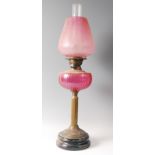 A Victorian brass pedestal oil lamp, having cranberry tinted acid etched shade over a cranberry