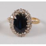 A yellow and white metal, sapphire and diamond oval cluster ring, featuring a centre oval faceted