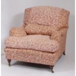 A Howard style floral upholstered armchair, having a deep cushioned seat, raised on bun turned