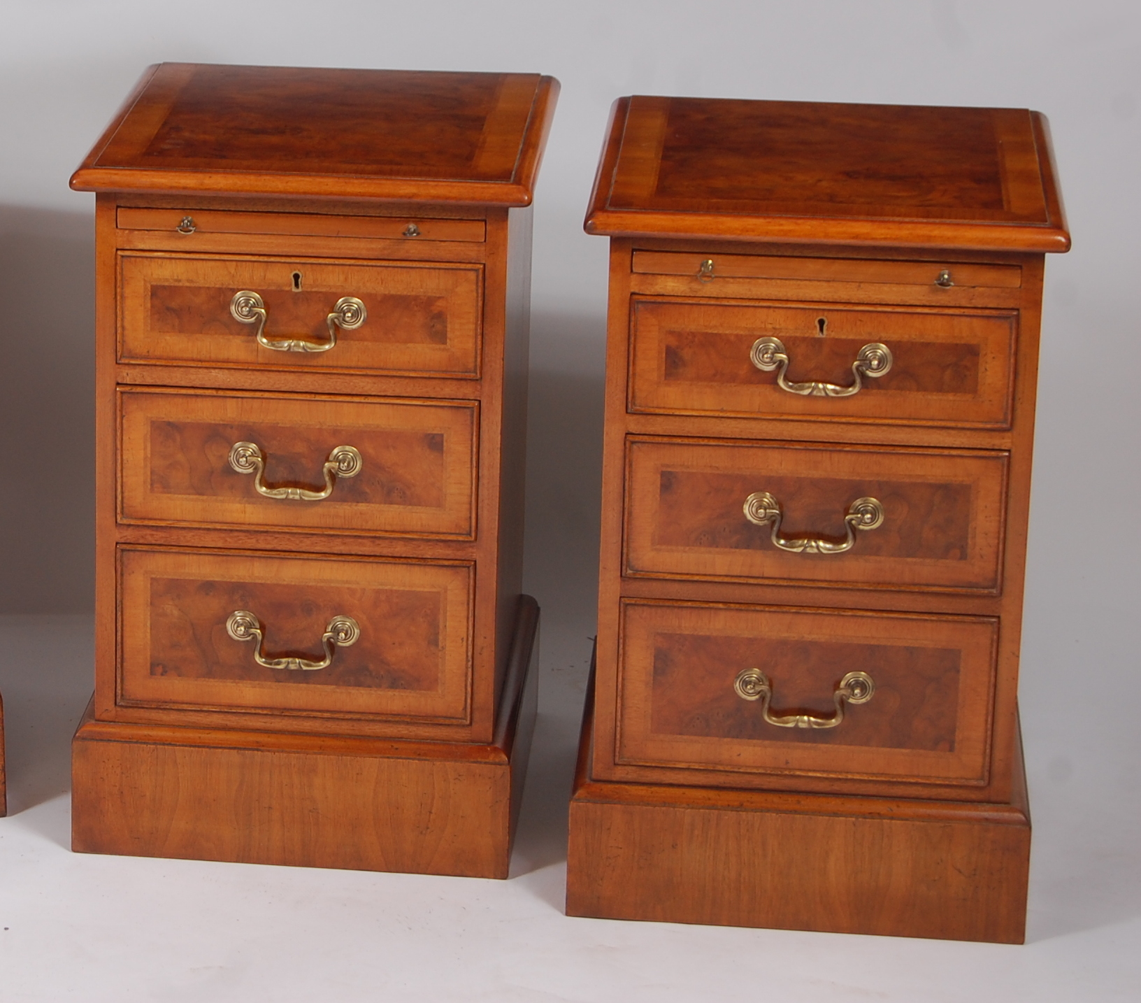 A pair of figured walnut cross and feather banded bedside chests, each having brushing slide over