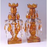 A pair of late 19th century Bohemian amber glass pedestal lustres, having multi-knopped and