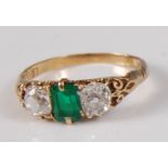 A late Victorian yellow metal, emerald and diamond three stone ring, comprising a centre octagonal