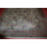 A Persian woollen green ground carpet, of good size, decorated with three rows of medallions each