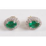 A pair of 18ct yellow and white gold oval emerald and diamond cluster earrings, in claw settings,