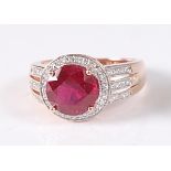 A rose gold, ruby and diamond circular cluster ring, featuring a centre round faceted ruby within
