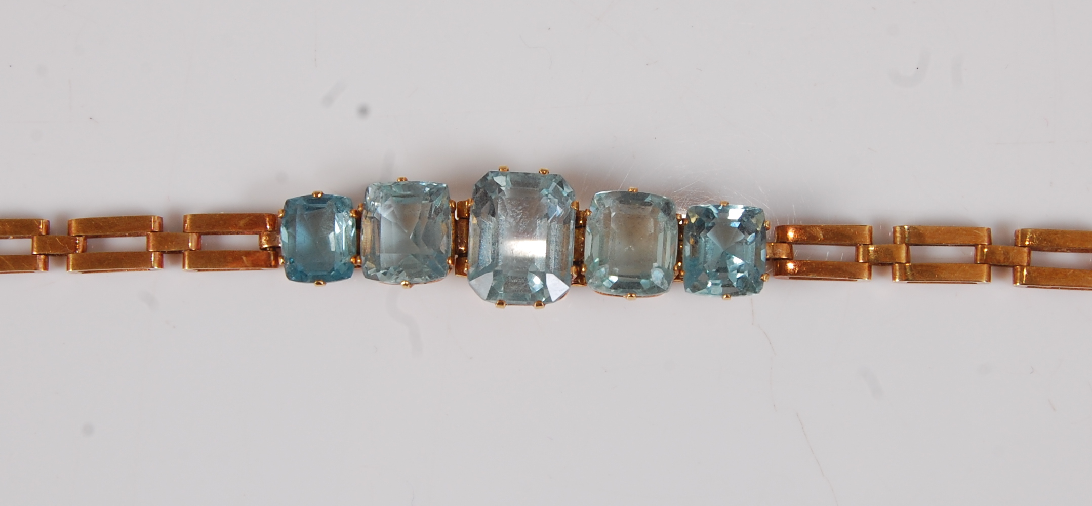 A yellow metal aquamarine bracelet, featuring five graduated octagonal cut aquamarines in claw