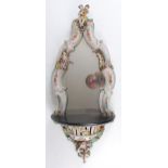 A 19th century German porcelain wall mirror, probably by Meissen , the shaped plate in a C-scroll