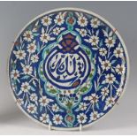 A Persian pottery small charger, underglaze decorated in tones of blue, green and brown, with
