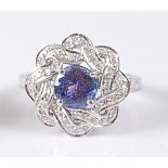 A white metal, tanzanite and diamond circular cluster ring, comprising a centre round faceted