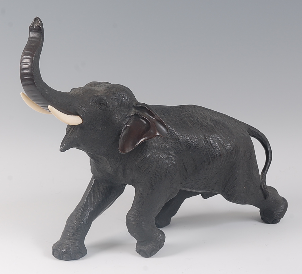 A Japanese Meiji period (1868-1912) bronze elephant, in striding pose, its trunk raised, all over