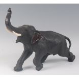 A Japanese Meiji period (1868-1912) bronze elephant, in striding pose, its trunk raised, all over