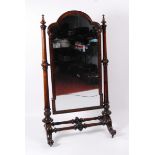 An early Victorian mahogany framed cheval mirror, the three quarter length mirror having a shaped