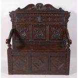 An antique carved and joined oak settle, circa 1700 and later, the three panelled back with blind