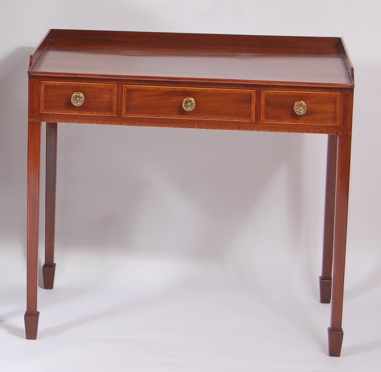 An early 19th century mahogany crossbanded and chequer strung three-quarter gallery back side table,