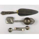 A silver tea strainer together with a silver vesta, two silver salt spoons, a silver handled cake