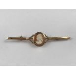 A 9ct gold and carved cameo bar brooch, the latter being collet set and held within bifurcated