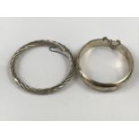 Two Elizabeth II silver hinged bangles, one of cabled form, together with one further of hollow D-