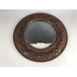 A late 19th / early 20th century carved hardwood framed circular wall mirror, 33 cm diameter