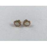 A pair of opal and 9ct gold stud earrings, the oval cabochons being claw-set within pelleted C-
