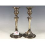 A pair of Edwardian silver candlesticks, having inverted and faceted bell-form sockets, above