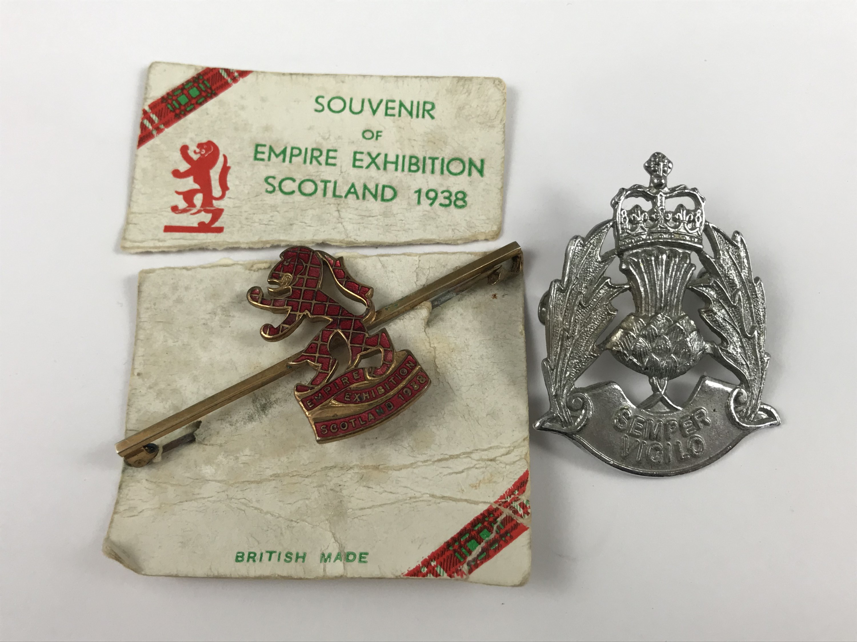 A 1938 Empire Exhibition Scotland enamelled bar brooch on original retail card, and a police badge