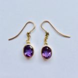 A pair of amethyst ear pendants, each having an oval-cut amethyst of approximately 1.25ct, collet-