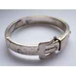 An Elizabeth II silver hinged bangle in the form of a buckled belt, bright-cut engraved with