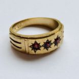 A 9ct gold and garnet ring, the broad tapering band having a faceted face surmounted by a combed and