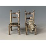 A pair of continental white-metal miniature rush seated chairs, one with the seated figure of a