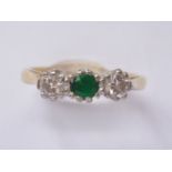 A vintage three-stone diamond and emerald dress ring, the central emerald of approximately .20ct,