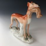 A 19th century Staffordshire pottery figurine of a greyhound clutching a rabbit in its mouth, 20 cm