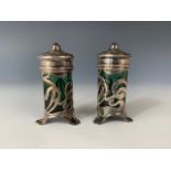 A pair Edwardian Art Nouveau silver pepperettes, of cylindrical form raised over three spreading