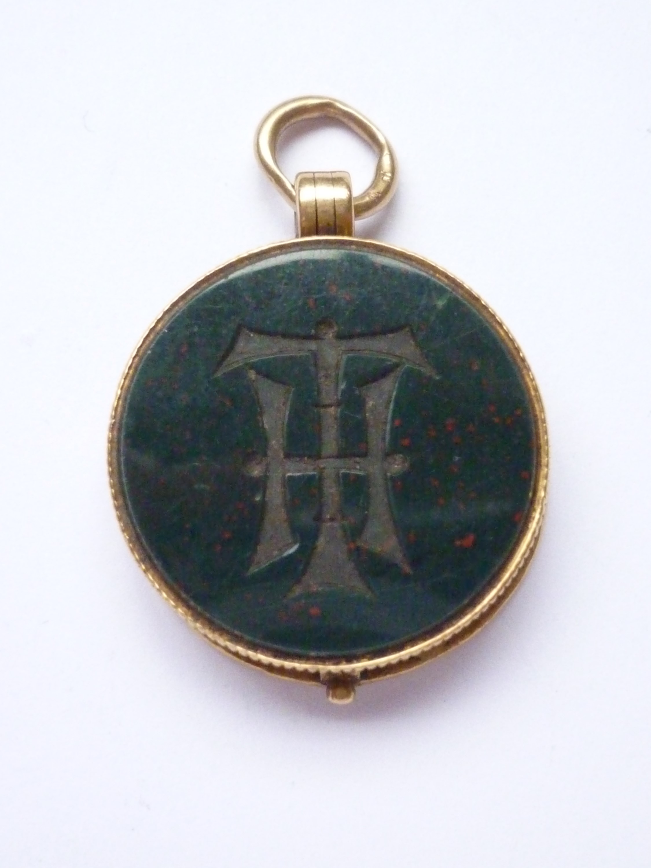 A Victorian locket fob fabricated from a George III gold spade guinea and bloodstone matrix, the