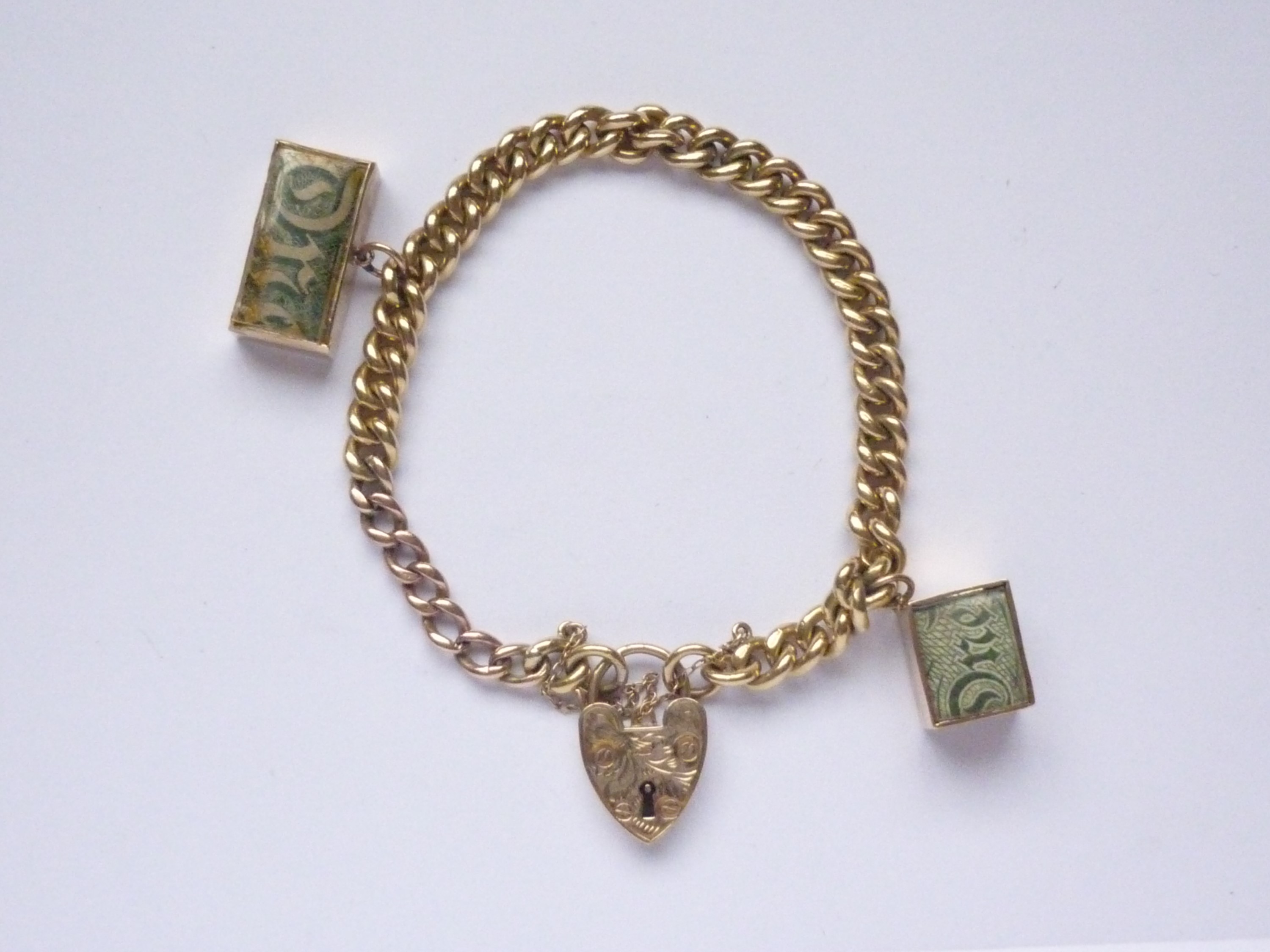 A 9ct gold curb-link charm bracelet, with heart-shaped padlock clasp and two 9ct gold pendant charms