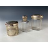 A set of three Art Nouveau silver and cut-glass dressing table jars, each having repousse-moulded
