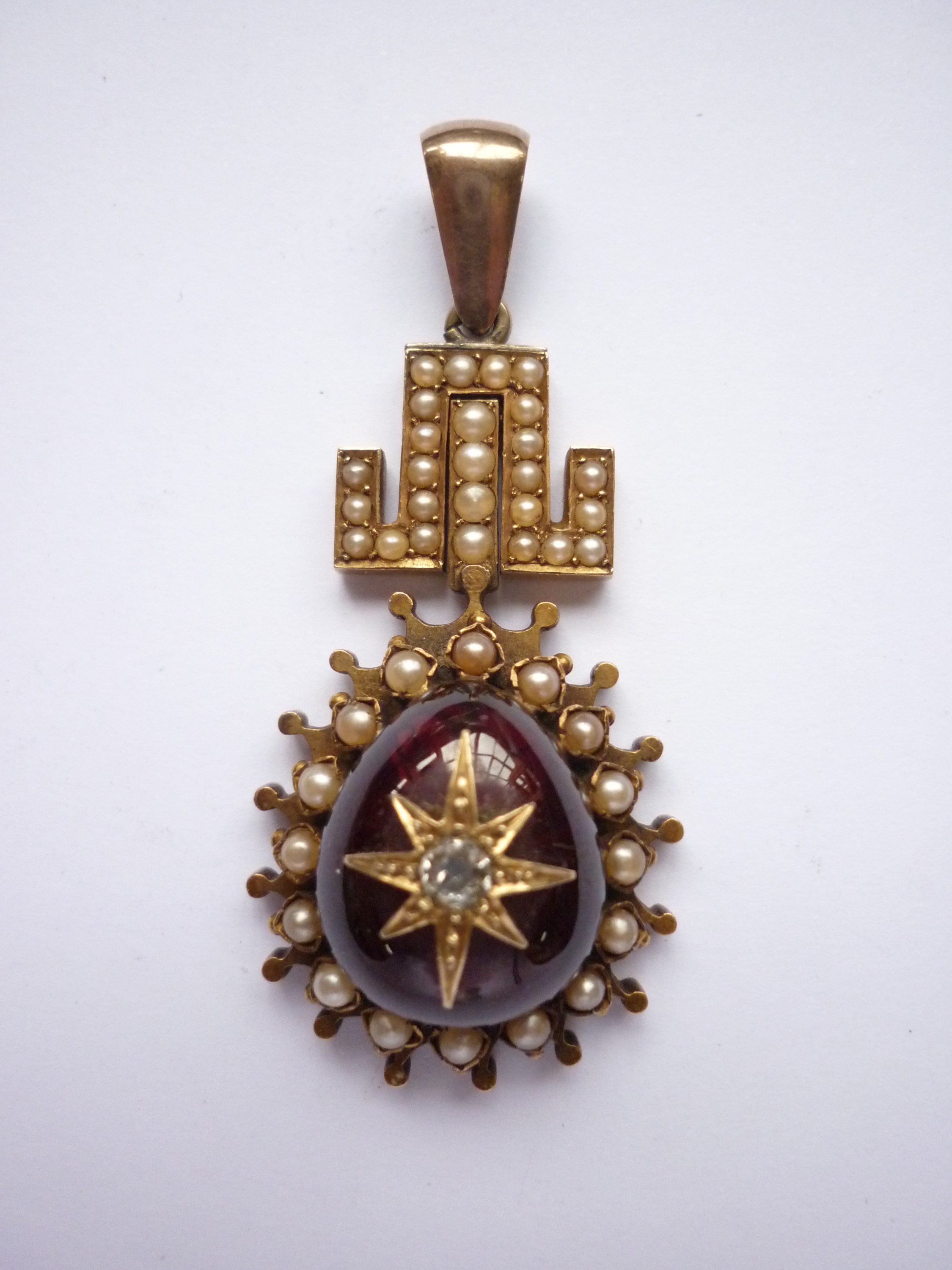 A Victorian diamond, garnet and pearl pendant of antique influence, having a pivoting Greek key