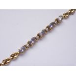 A high carat yellow-metal, diamond and tanzanite bracelet, having five oval-cut and claw set