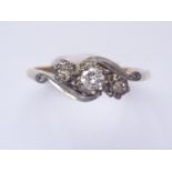 A three-stone diamond ring, the central brilliant-cut stone of approximately .10ct, illusion-set and